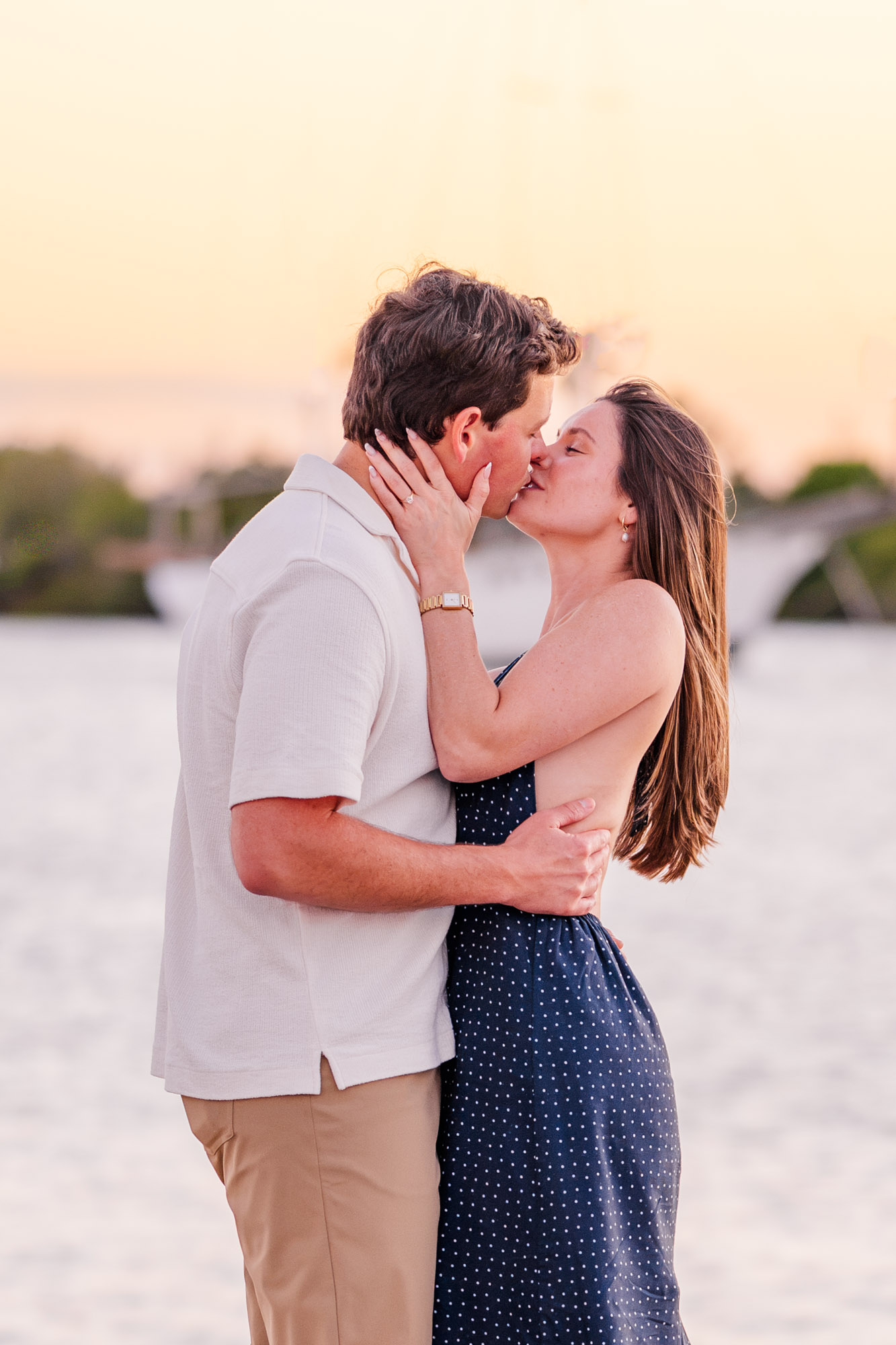 Couple embracing beside white roses, candles, and champagne during their romantic Melbourne, Florida proposal.