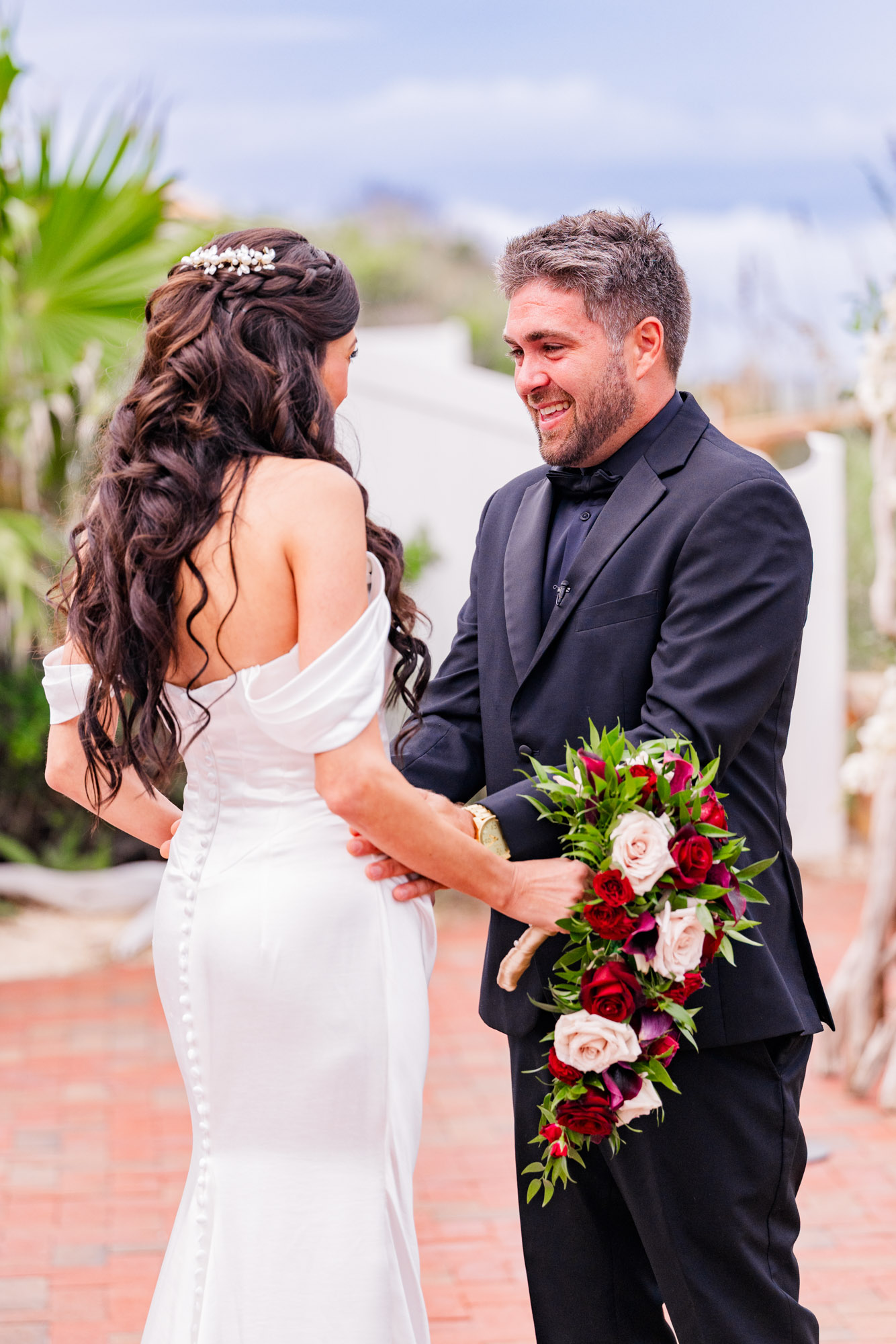 Groom laughing through tears as he holds his bride’s arms after their first look