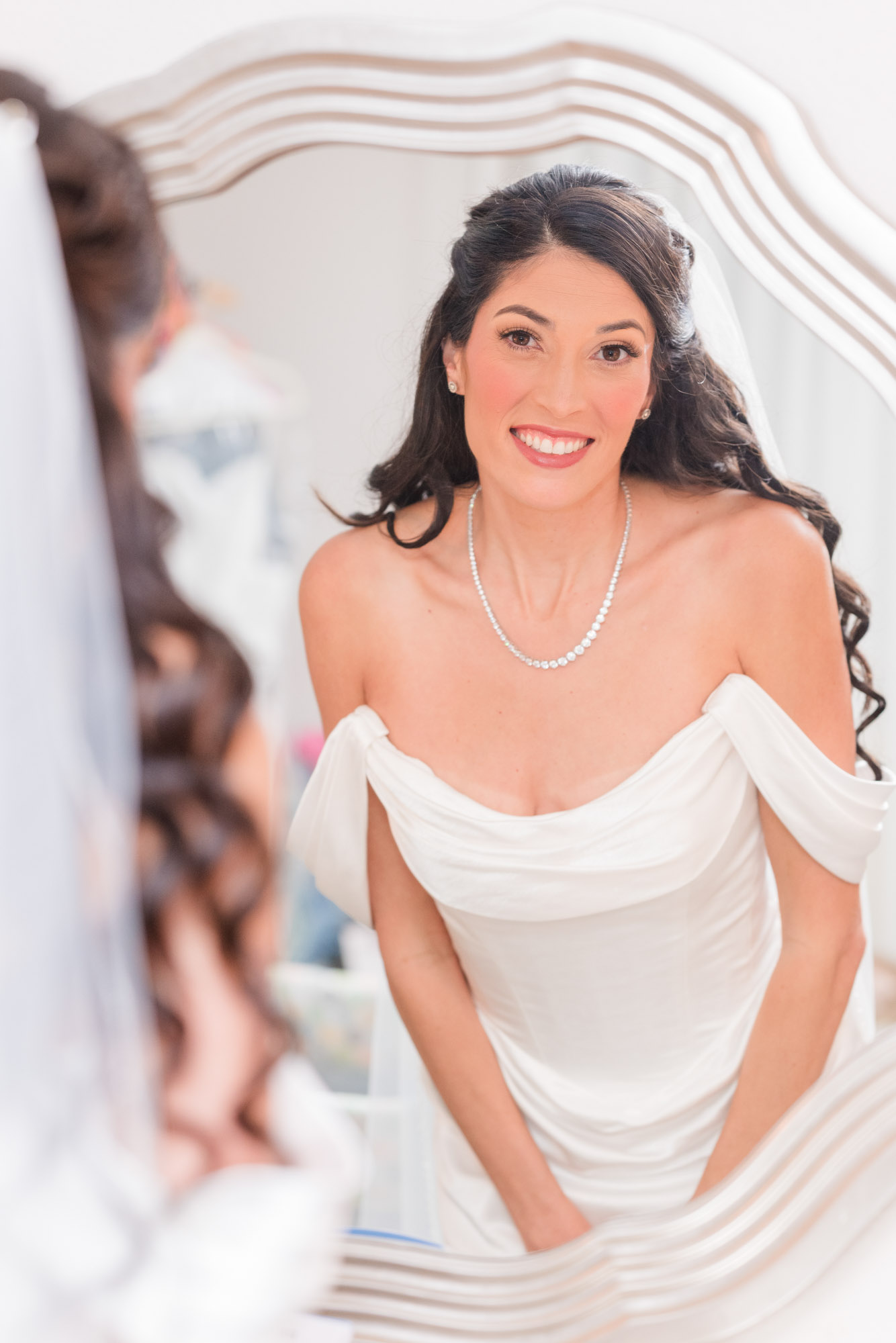 Bride smiling at her reflection in the bridal suite mirror before the ceremony