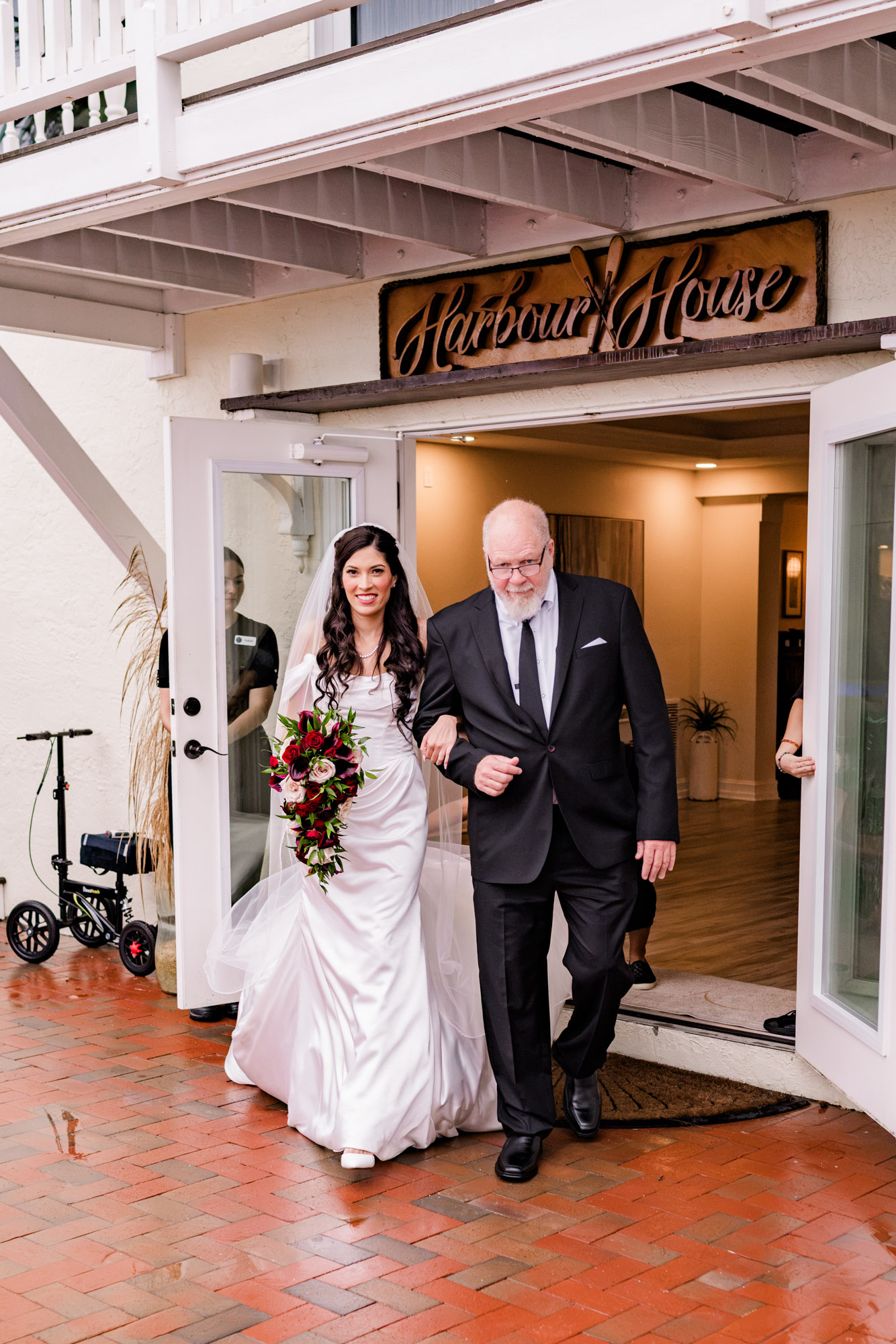 Bride and her father walking out to the ceremony beneath the Harbour House sign