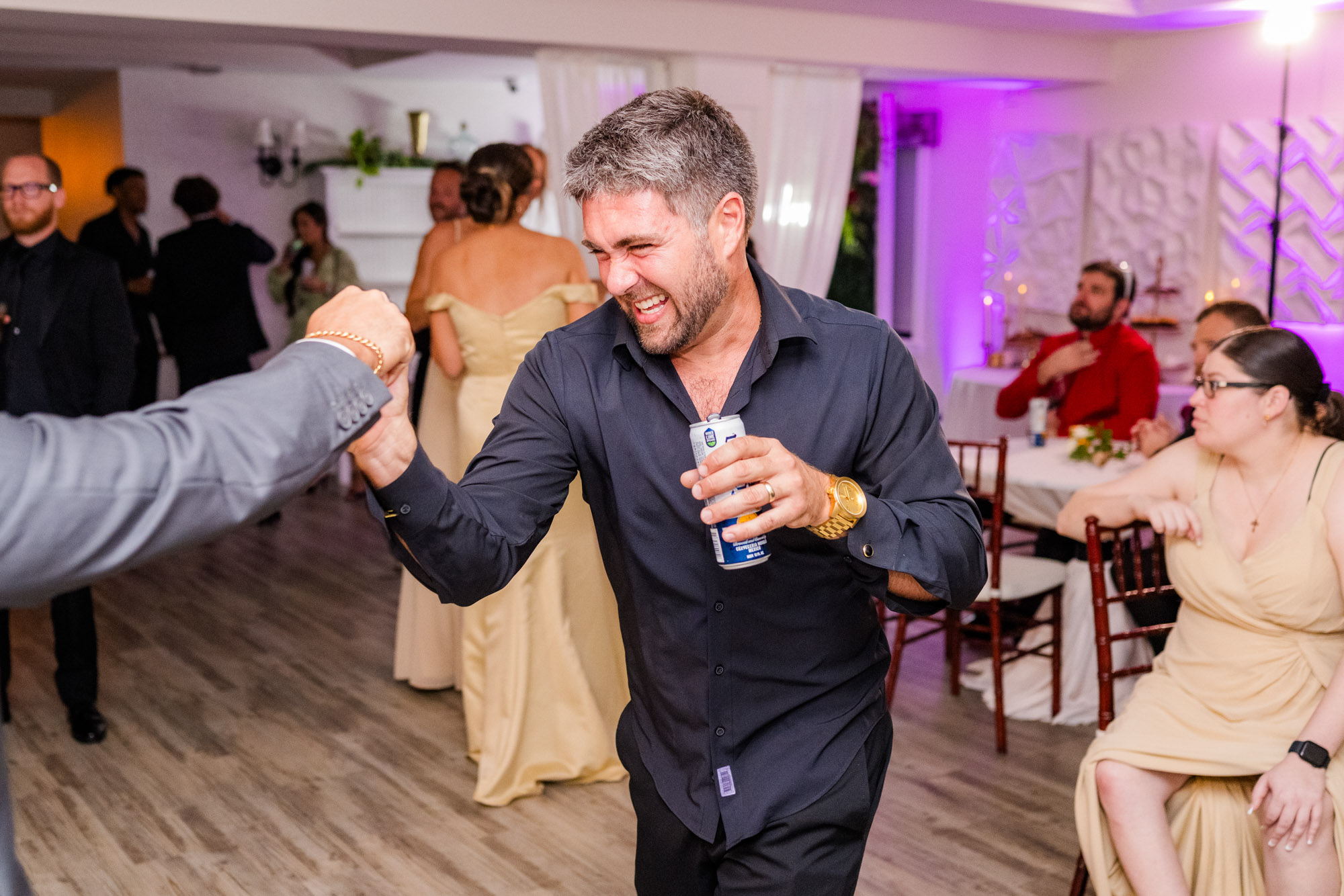 Groom fist-bumping a guest on the dance floor, both laughing