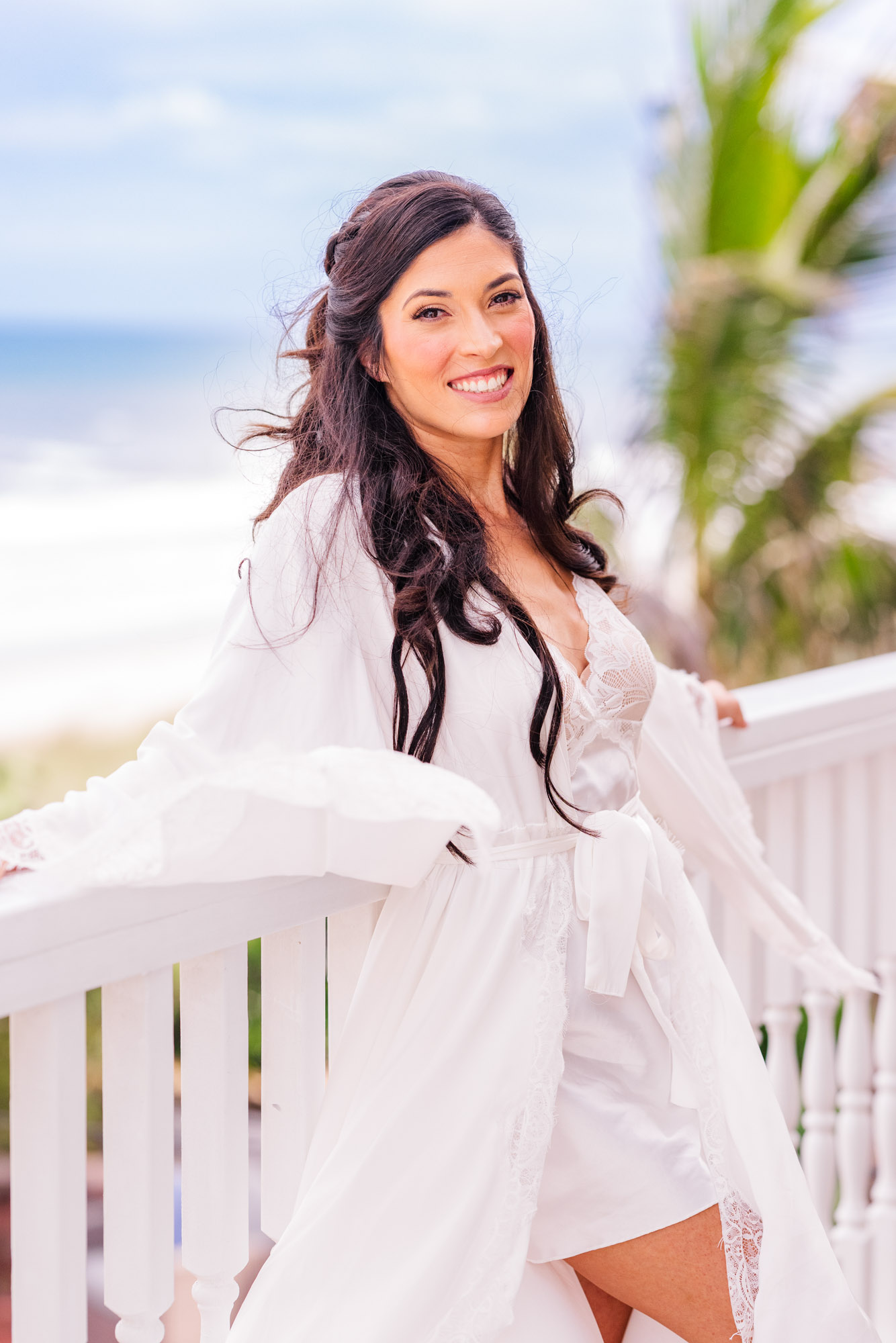 Bride in a white lace robe twirling on the oceanfront deck at Harbour House Oceanfront, Melbourne Beach