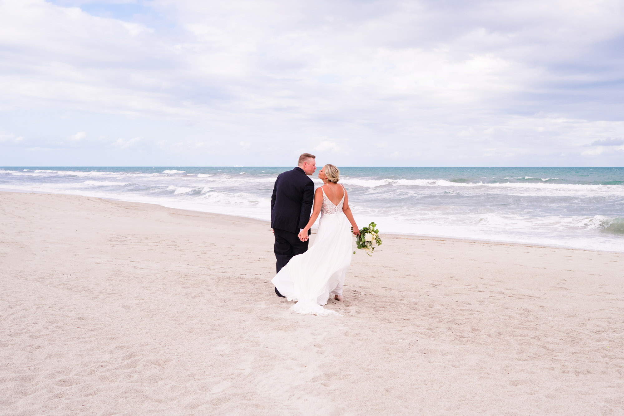 Couple walking away down the beach with the ocean in the background