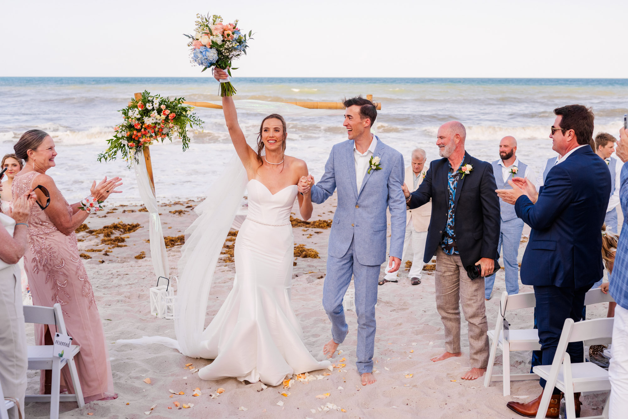 Bride with arm in the air celebrating after getting married on the beach at the Hilton Melbourne beach Oceanfront