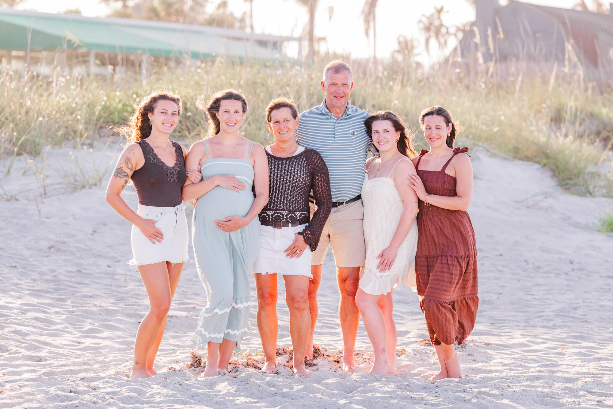 Extended family smiling together in coordinated neutral and earth-tone outfits on the beach.