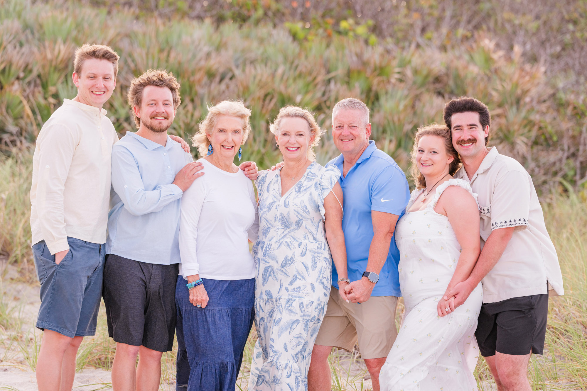 Large family smiling together during an extended family beach photo session.