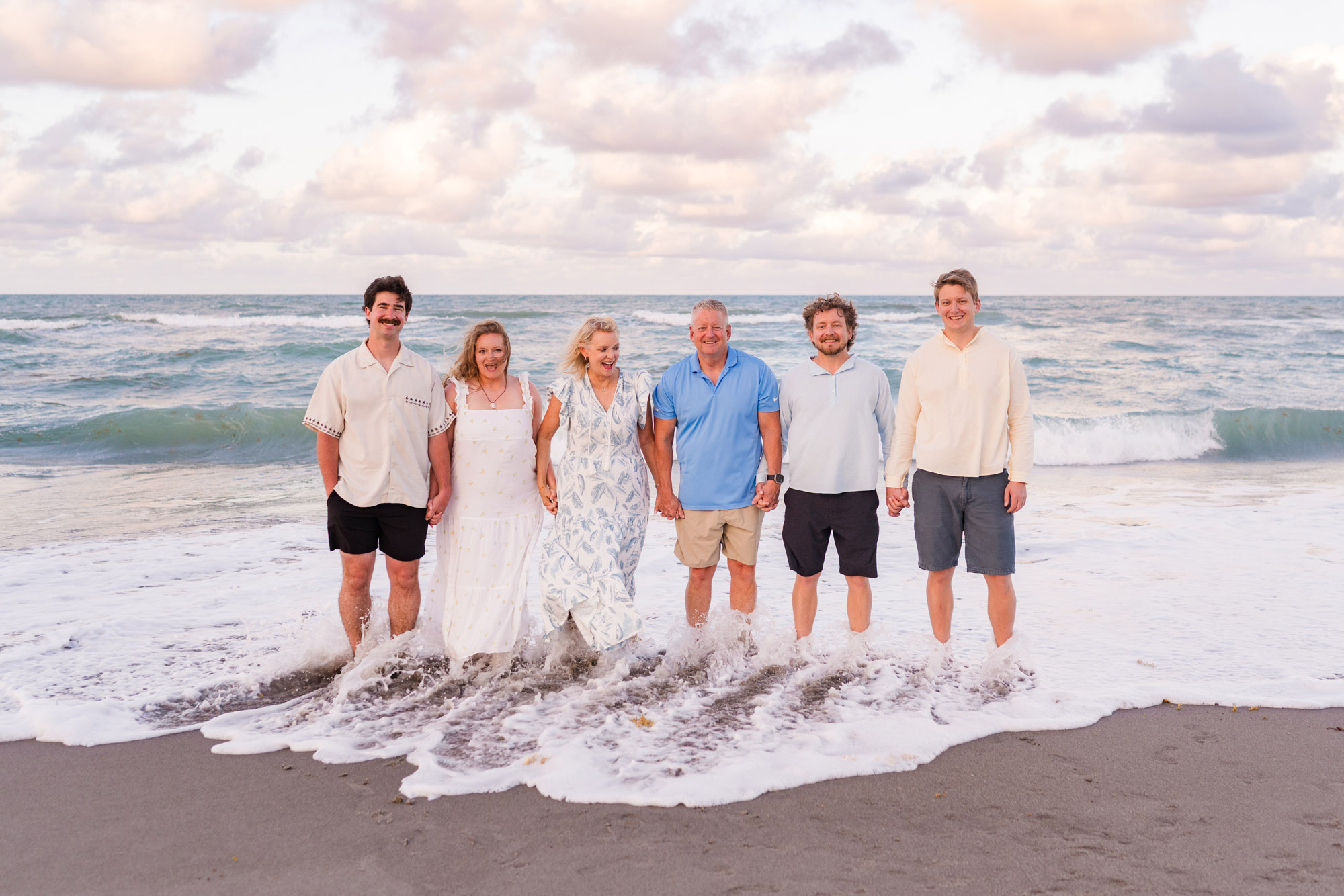 Family walking through the surf together during a beach photo session on Florida’s Space Coast.
