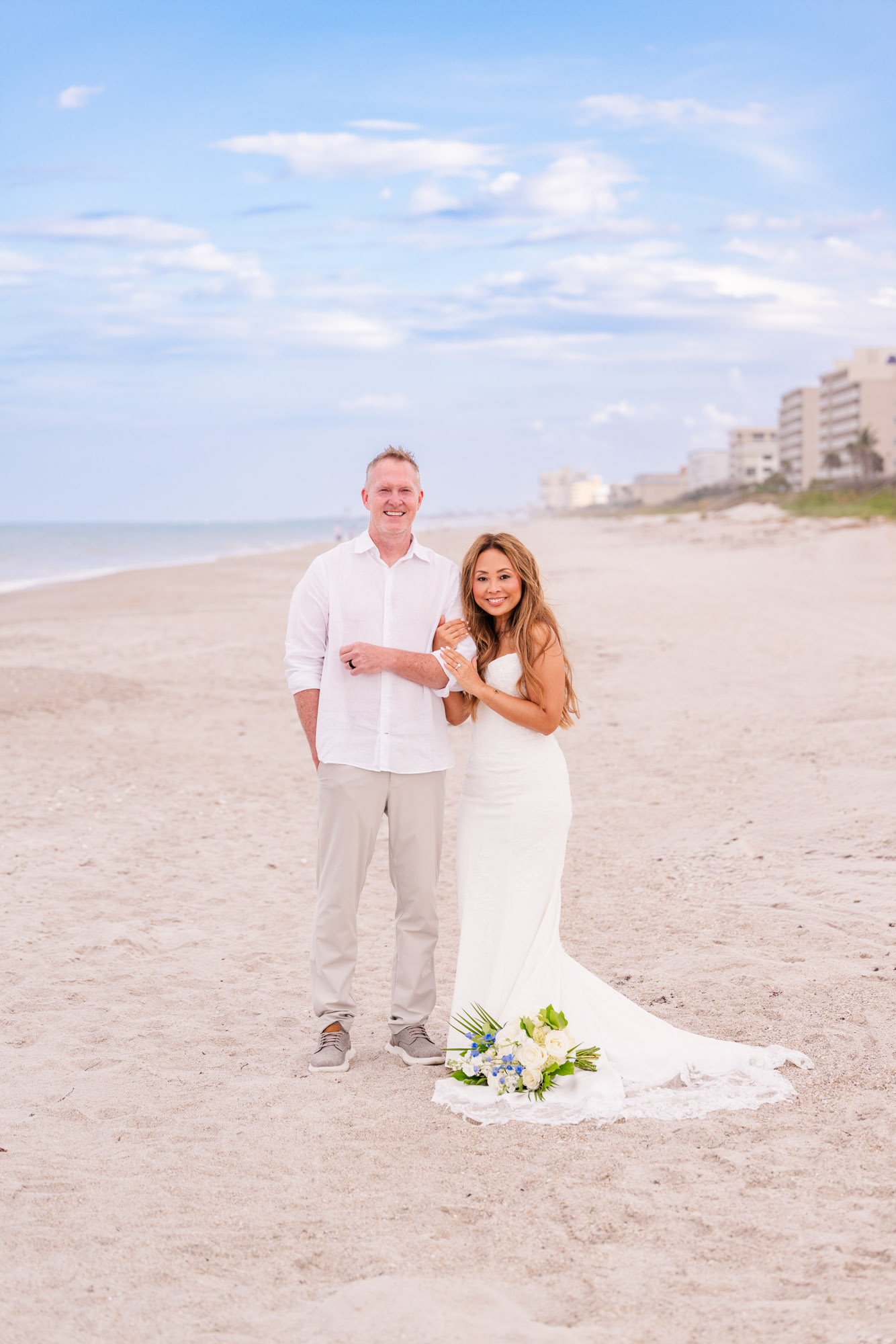 Bride and groom posing together on a quiet stretch of Melbourne Beach following their intimate oceanfront wedding ceremony.
