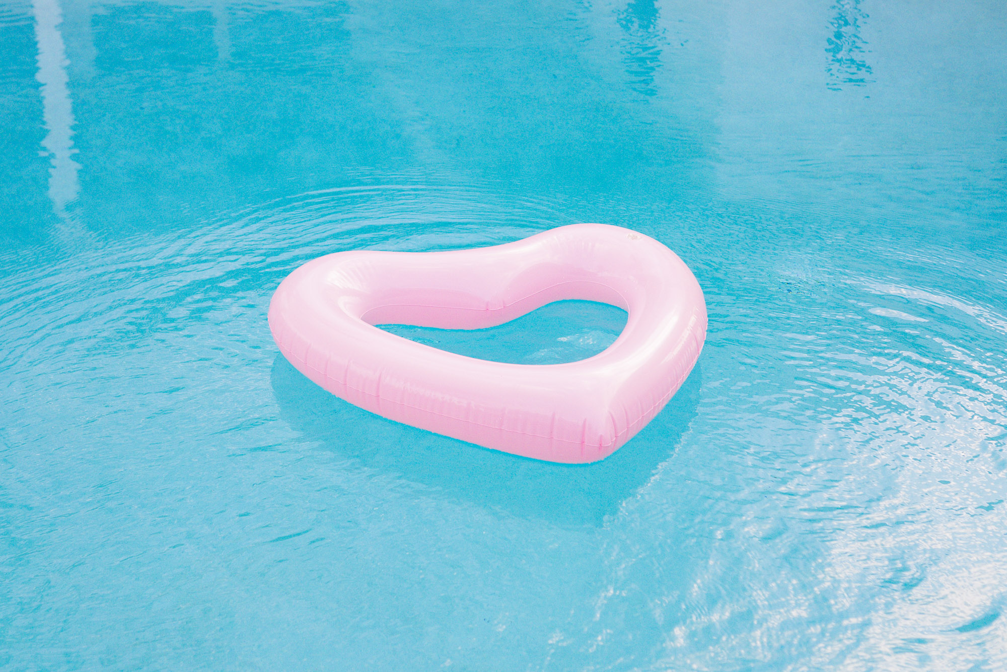 a pink floating heart in a aqua blue pool