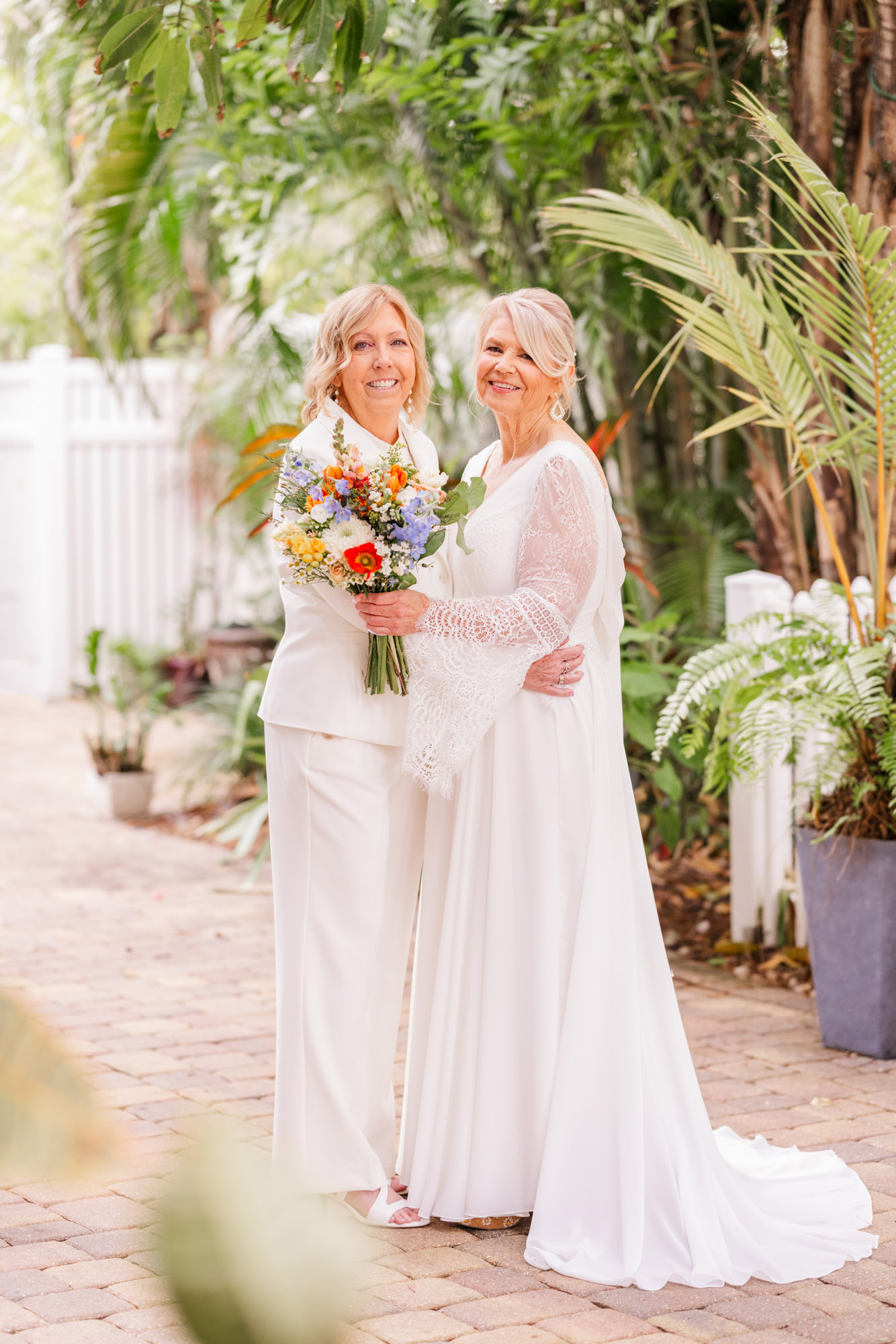 Two brides dressed in white posing in the tropical garden at the Seaglass Inn in Melbourne Beach