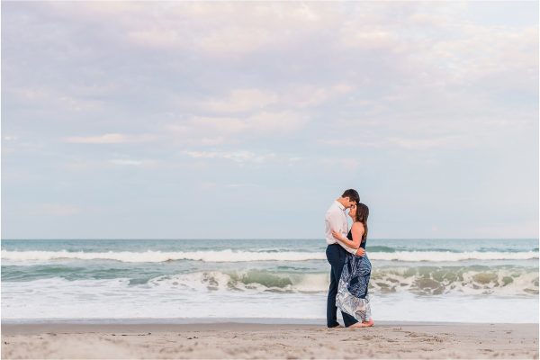 Couple hugging with ocean in background Best Engagement Session Beach Locations