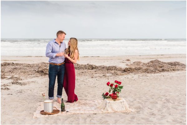 Couple toasting on beach after getting engaged during Cocoa Beach Surprise Proposal
