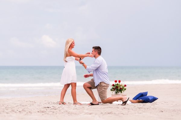 man on beach down on his knee asking his girlfriend to marry him on Melbourne Beach, Florida