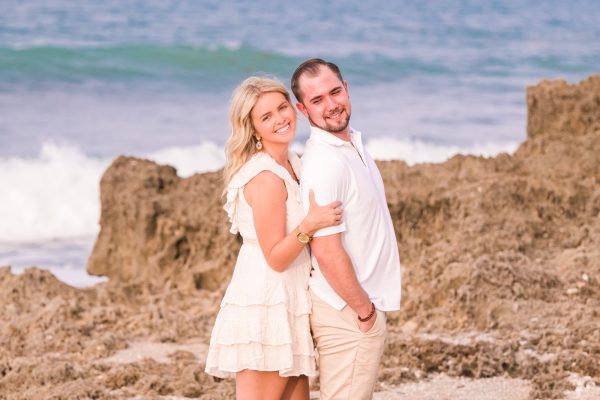 Couple in white and tan hugging on the beach in Jupiter, Florida