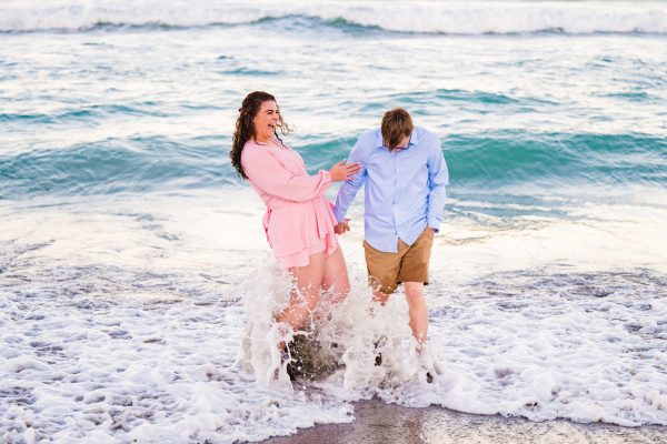 Couple in pink and blue laughing at the beach